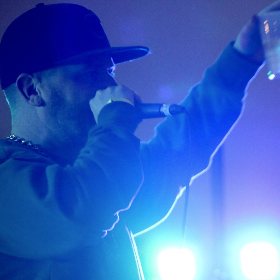 Rel McCoy on stage, on the mic under blue lights